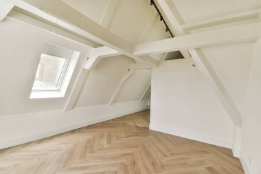 Parlak ve minimalist tavan arası. Ahşap döşeme ve açılı tavanlar, çağdaş tasarım estetiğini vurguluyor..