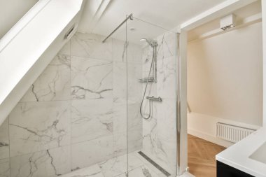 Zarif mermer duvarlar, temiz çizgiler ve şık banyo için ideal minimalist armatürler içeren gösterişli ve çağdaş bir duş alanı..