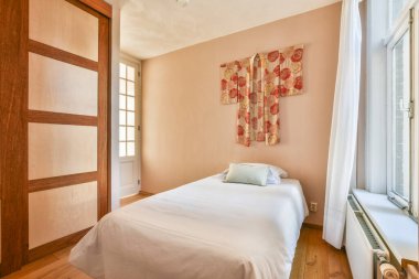 Huzurlu bir yatak odası. Minimalist dekorlar, yumuşak renkler ve rahatlamak için mükemmel bir ortam yaratan eşsiz bir duvar..