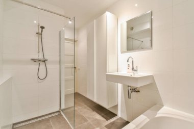 Cam duş, minimalist lavabo ve modern aksesuarların olduğu gösterişli, modern bir banyo. Temiz çizgiler ve nötr renkler sakin bir atmosfer yaratır..