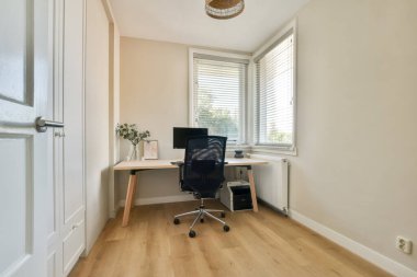 Moda ve minimalist bir ev ofisi. Masası, sandalyesi ve bilgisayarı olan, doğal ışık alan bir pencere..