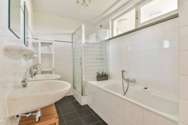 Küvet, duş ve şık lavaboların olduğu parlak ve çağdaş bir banyo. Doğal ışık, minimalist elementlerle temiz tasarımı geliştirir..