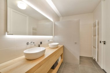 Pürüzsüz, modern bir banyo. Temiz çizgileri, basit armatürleri ve nötr renkleri olan minimalist bir tasarım. Huzurlu bir atmosfer yaratıyor..
