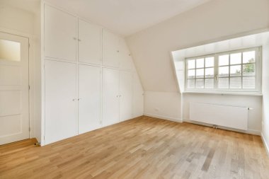 Geniş ve minimalist bir iç mekan. Temiz beyaz duvarlar, bir gardırop ve geniş bir pencereden geniş bir doğal ışık. Modern yaşam için mükemmel..