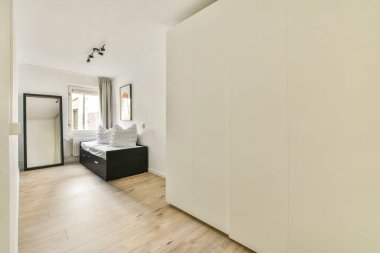 Huzurlu, minimalist bir yatak odası, rahat bir yatak odası, açık renkli duvarlar, ve rahatlatıcı bir atmosfer için pencereden akan bol miktarda doğal ışık..