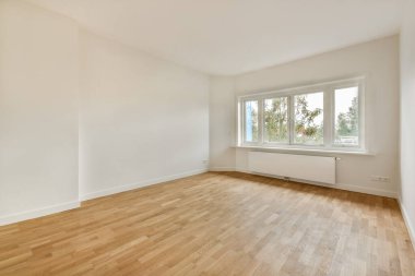 Parlak ve havadar bir oda. Minimalist iç tasarımı sergiliyor. Büyük pencerelerden ve zarif ahşap döşemelerden doğal ışık yayılıyor..