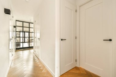 Gösterişli ve modern bir koridor şık kapılar ve sıcak ahşap bir zemin, davetkar bir atmosfer yaratıyor. Doğal ışık minimalist tasarımı geliştirir.