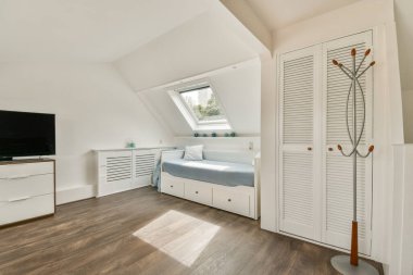 Konforlu bir yatak odası, minimalist bir dekor ve pencerelerden süzülen geniş doğal ışık. Ahşap zemin boşluğa sıcaklık katar..