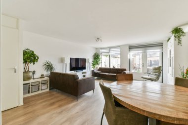 Minimalist mobilyaların, büyük pencerelerin ve kapalı mekanların bulunduğu modern bir oturma odası rahatlama ve sosyalleşme için mükemmel bir ortam yaratıyor..