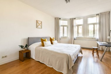 Parlak ve havadar modern bir yatak odası, rahat bir yatak odası, sıcak ahşap döşemeler, ve pencerelerden süzülen yumuşak doğal ışık, minimalist tasarımını geliştiriyor..