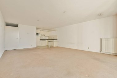 Geniş, modern oturma odası bej halı, beyaz duvarlar ve minimalist tasarım. Ev dekorasyonu veya iç dekorasyon için ideal.