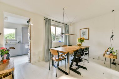 Şık, modern bir yemek odası, ahşap bir masa, zarif sandalyeler, ve uzayın davetkar atmosferini arttıran zevkli dekorasyonlar..