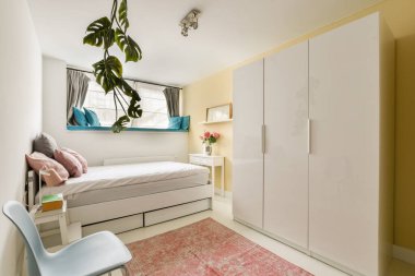 Yumuşak renkleri olan minimalist bir tasarımı olan şık ve rahat bir yatak odası, şık bir yatak odası, beyaz mobilyalar, ve uzaya sıcaklık katan dekoratif bir halı..