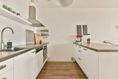 Minimalist dolaplar, paslanmaz çelik aletler ve sıcak ahşap döşemeler içeren şık ve modern bir mutfak, şık bir mutfak alanı yaratıyor..