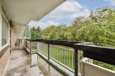 Modern bir balkon yemyeşil bir manzaraya bakar. Rahatlamak ve doğal güzelliklerden zevk almak için davet edici bir alan sunar..