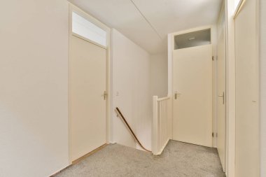 Beyaz duvarları ve kapıları olan minimalist bir tasarımı olan parlak ve havadar bir koridor. İnce bir merdivenle aksanlı. Temiz çizgiler şık bir ortam yaratıyor..