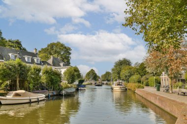 Berrak mavi gökyüzünün altında büyüleyici teknelerin ve tuhaf evlerin bulunduğu, doğada sükunet ve güzelliği çağrıştıran görkemli bir kanal sahnesi..