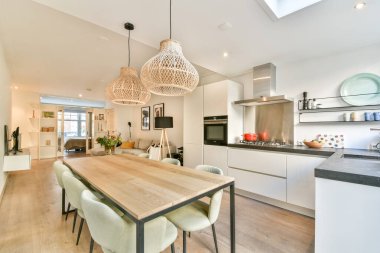 Zarif ışıklandırma, ahşap yemek masası ve modern yaşam için mükemmel bir mutfak düzeni olan modern mutfak ve yemek odası..