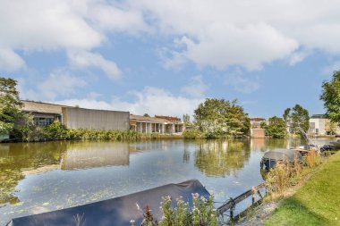 Çağdaş binalar ve verimli yeşilliklerle çevrili sakin bir gölü yansıtan sakin bir manzara..