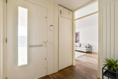 Beyaz kapısı olan şık bir iç mekan ve ötesinde rahat bir yaşam alanını aydınlatan parlak, doğal bir ışık. Ahşap zemin modern tasarıma sıcaklık katıyor..