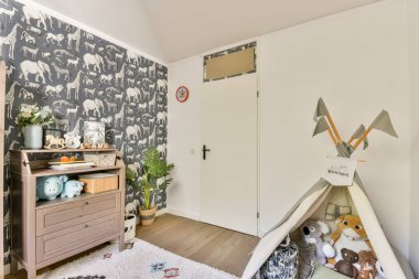 Oyuncak fil duvar kağıtlarının olduğu büyüleyici bir çocuk odası doldurulmuş hayvanlarla dolu rahat bir çadır ve sıcak bir atmosfer yaratan dekoratif elementler..