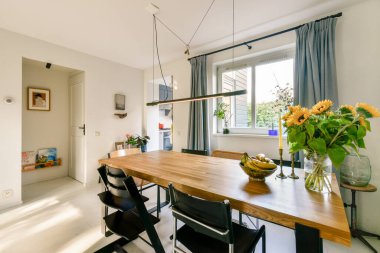 Ahşap bir masa, zarif sandalyeler ve taze çiçekler sergilenen parlak ve havadar bir yemek odası. Aile toplantıları ve yemekler için mükemmel..