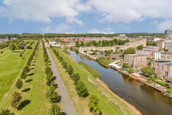 Kıyı boyunca kıvrımlı bir su yolu, yemyeşil ve modern binaların yer aldığı canlı bir şehir manzarasını gösteren güzel bir hava manzarası..