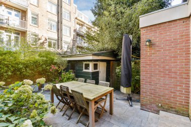 Etrafı yeşillik ve küçük bir barakayla çevrili, ahşap bir masası ve sandalyeleri olan huzurlu bir bahçe. Rahatlamak ya da sosyal toplantılar için mükemmel..