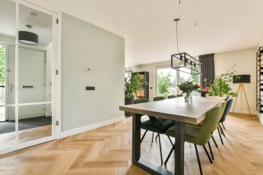 Modern mobilyaların, iyi ışıklandırılmış bir atmosferin ve uzayın genel estetiğini geliştiren davetkar dekorun bulunduğu şık bir yemek alanı..