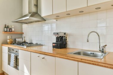 Gösterişli dolaplar, paslanmaz çelik eşyalar ve işlevsellik ve stil için tasarlanmış ahşap bir tezgah içeren çağdaş bir mutfak..