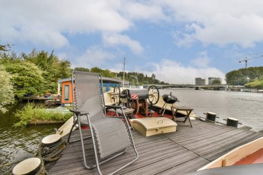 Nehirle çevrili, yeşil ve modern yapılarla çevrili, rahatlamak için mükemmel, sakin bir yüzen ev manzarası..