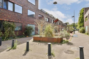 Canlı bir şehir manzarası. Çağdaş tuğla binalar, yemyeşil bitkilerle karışıyor. Alan hem estetik hem de işlevsellik için tasarlanmıştır..