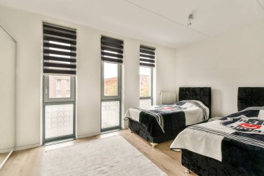 Geniş pencereleri, modern mobilyaları ve şık bir halısı olan gösterişli ve modern bir oturma odası, doğal ışığın içeri aktığı bir ortam yaratıyor..