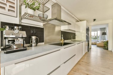 Minimalist tasarım elementleri, paslanmaz çelik aletler ve çağdaş atmosferi geliştiren sıcak ahşap zemin içeren gösterişli ve modern bir mutfak..