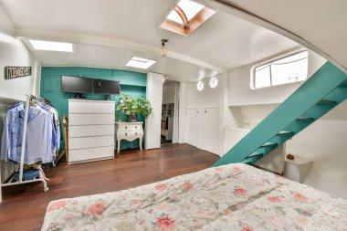 Modern tasarım elementleri ve konfor karışımı sergilenen şık mobilyalar, canlı renkler ve rahat bir atmosfer içeren çağdaş bir yatak odası..