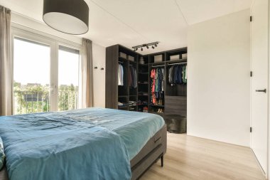 Geniş, modern bir yatak odası düzenli bir dolap, geniş pencereler, doğal ışığa izin veren, ve konforu ve estetiği arttıran şık mobilyalar..