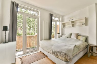 Geniş pencereli, yumuşak yataklı ve minimalist dekorlu parlak ve davetkar bir yatak odası. Rahatlamak ve rahatlamak için sakin bir atmosfer yaratıyor..
