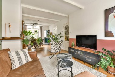 Lüks koltukları, ahşap zemini ve rahat atmosferi geliştiren çeşitli kapalı salonları olan modern bir oturma odası..