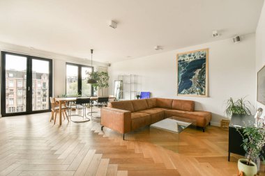 Bu çağdaş oturma odasında ortam ortamını geliştiren şık bir kanepe, ahşap döşeme ve canlı bir sanat eseriyle rahatlık ve zarafetin bir karışımı sergileniyor..