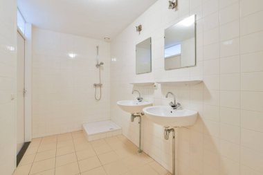 İkiz lavaboların, zarif aynaların ve fayanslı duvarların olduğu basit ve modern bir banyo. Tasarım temizliği ve işlevselliği vurguluyor.