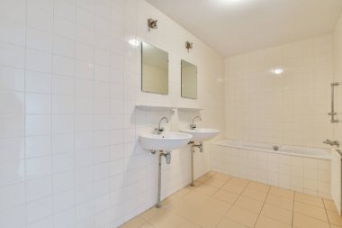 Temiz çizgiler, beyaz fayanslar, çift lavabo ve küvet içeren çağdaş bir banyo, minimalist ve ferah bir atmosfer yaratıyor..
