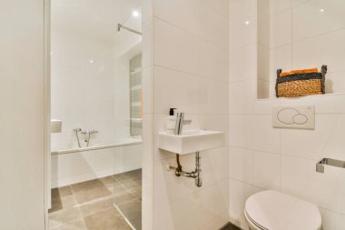 Temiz çizgiler ve nötr palet bu modern minimalist banyoyu tanımlar. Parlak armatürler ve geniş ışıklandırma rahatlamak için davetkar bir ortam yaratır..