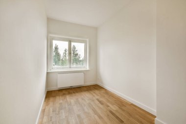 Doğal ışığın ahşap zemini aydınlatmasına izin veren geniş pencereli minimalist boş bir oda huzurlu ve ferah bir atmosfer yaratıyor..