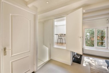 Pürüzsüz, iyi ışıklandırılmış bir iç mekan, temiz çizgiler ve rahat bir ortam yayan minimalist mobilyalarla tamamlanmış açık manzaralı bir pencere sergiliyor..
