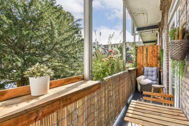 Konforlu bir balkon, ahşap aksanlar, rahat koltuklar ve canlı bitkiler. Rahatlamak ve eğlenmek için ideal şehir ortamında güzellik.