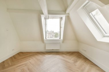 Açılı pencereleri, ahşap zemini ve çağdaş yaşam alanları için ideal minimalist tasarım elemanlarını barındıran parlak ve ferah bir iç mekan..