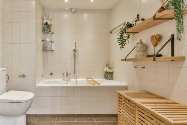 İnce çizgiler ve doğal elementler içeren bu minimalist banyo, sakin bir atmosfer için ahşap aksanlar ve bitkiler içeriyor..
