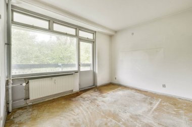 Geniş, boş bir oda geniş bir pencereye sahip doğal ışığın boşluğu doldurmasına olanak sağlıyor. Zemin boş, tasarım değişikliği potansiyeli var..