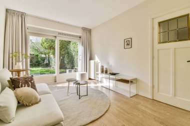 Rahat bir kanepe, şık bir dekor, doğal ışık getiren büyük pencereler ve rahatlamak için mükemmel sıcak bir atmosfer olan şık bir oturma odası..