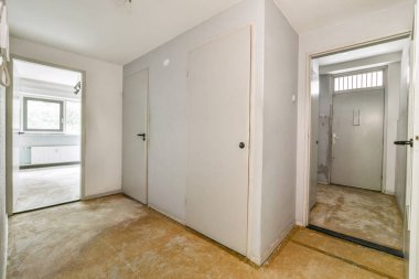 Geniş, boş bir koridor, düz duvarlar, basit kapılar ve aydınlatılmamış bir ortam, minimalist bir tarzı işaret ediyor. Ev yenileme konseptleri için ideal.
